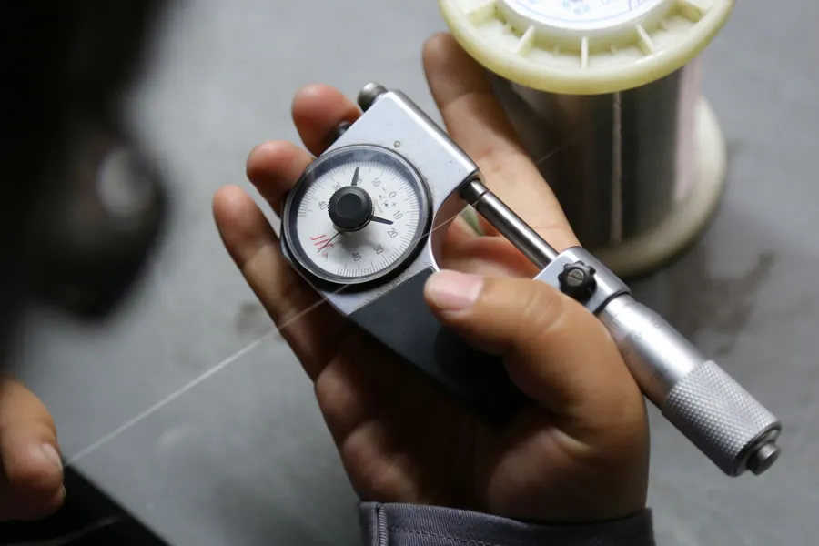 Technicien mesurant la tension d’un fil en acier inoxydable avec une jauge portative