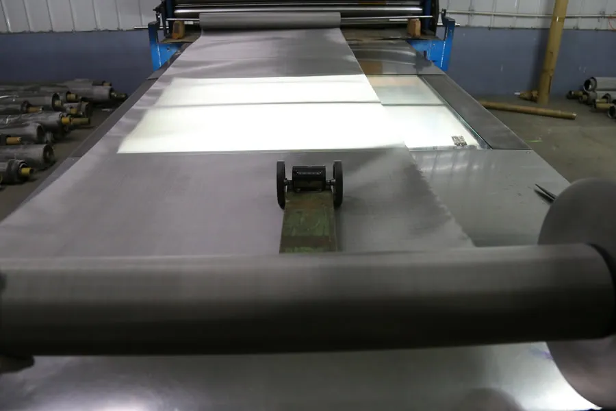 Toile métallique en acier inoxydable passant sur une table d’inspection éclairée