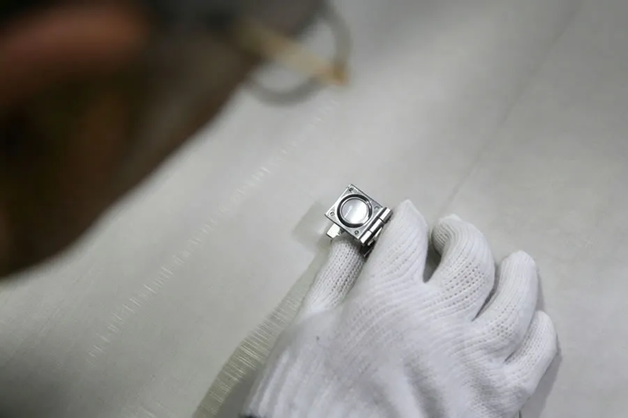 Inspecteur utilisant une loupe pliante pour examiner une toile métallique en acier inoxydable